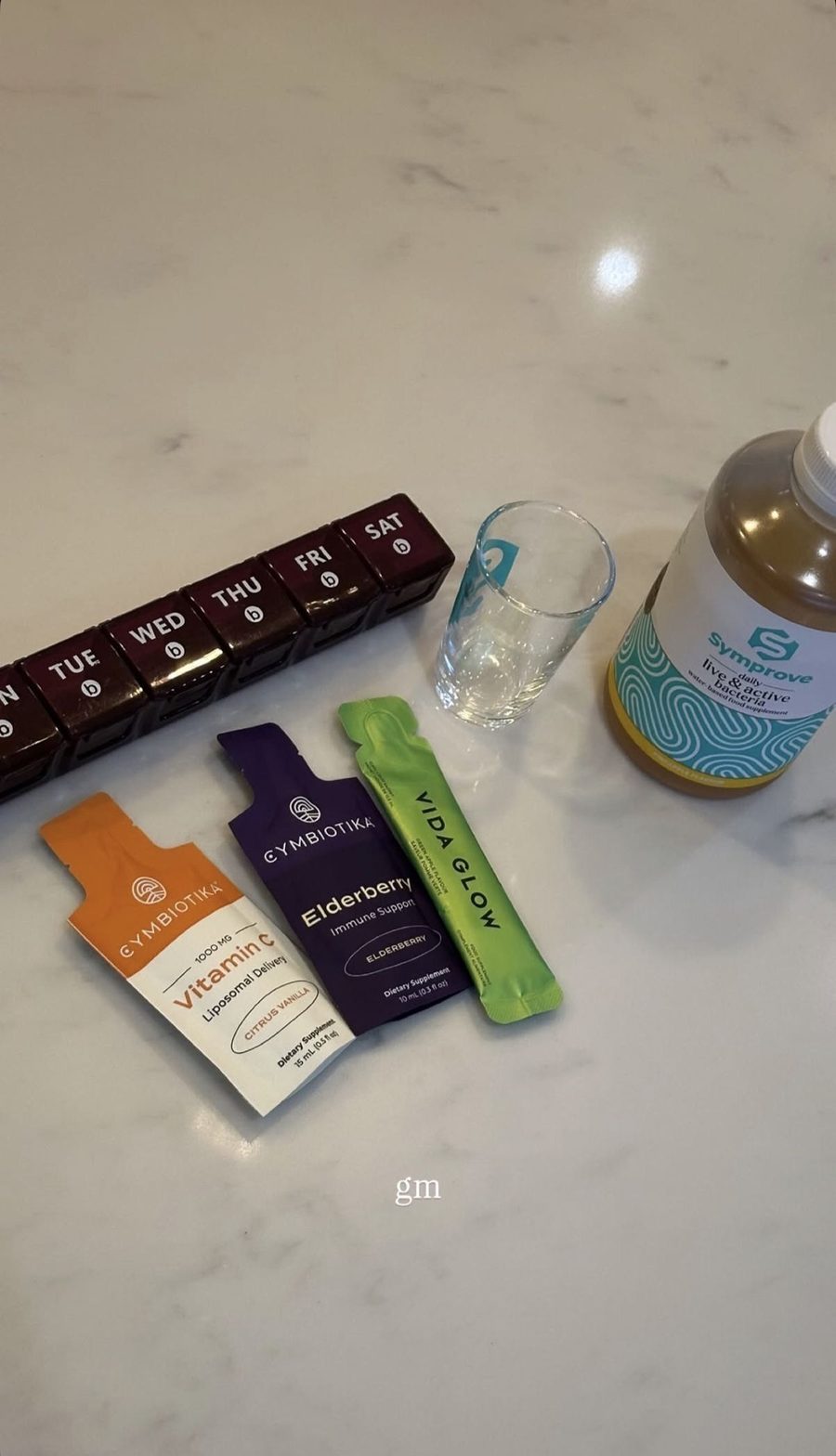 A morning supplement routine: a pill organiser and several products beside a glass of water