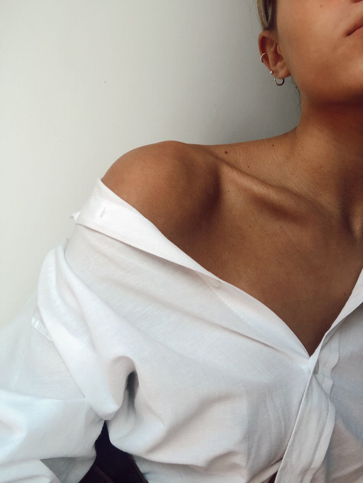 Close-up of a woman's neck and collarbone in a white shirt, editorial style