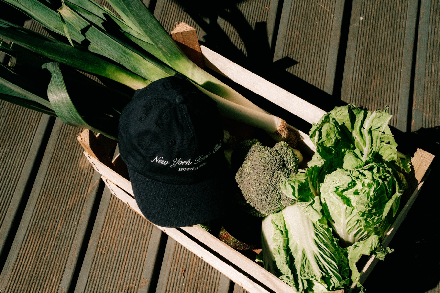 Fresh vegetables in a wooden crate — leek, broccoli, cabbage and lettuce